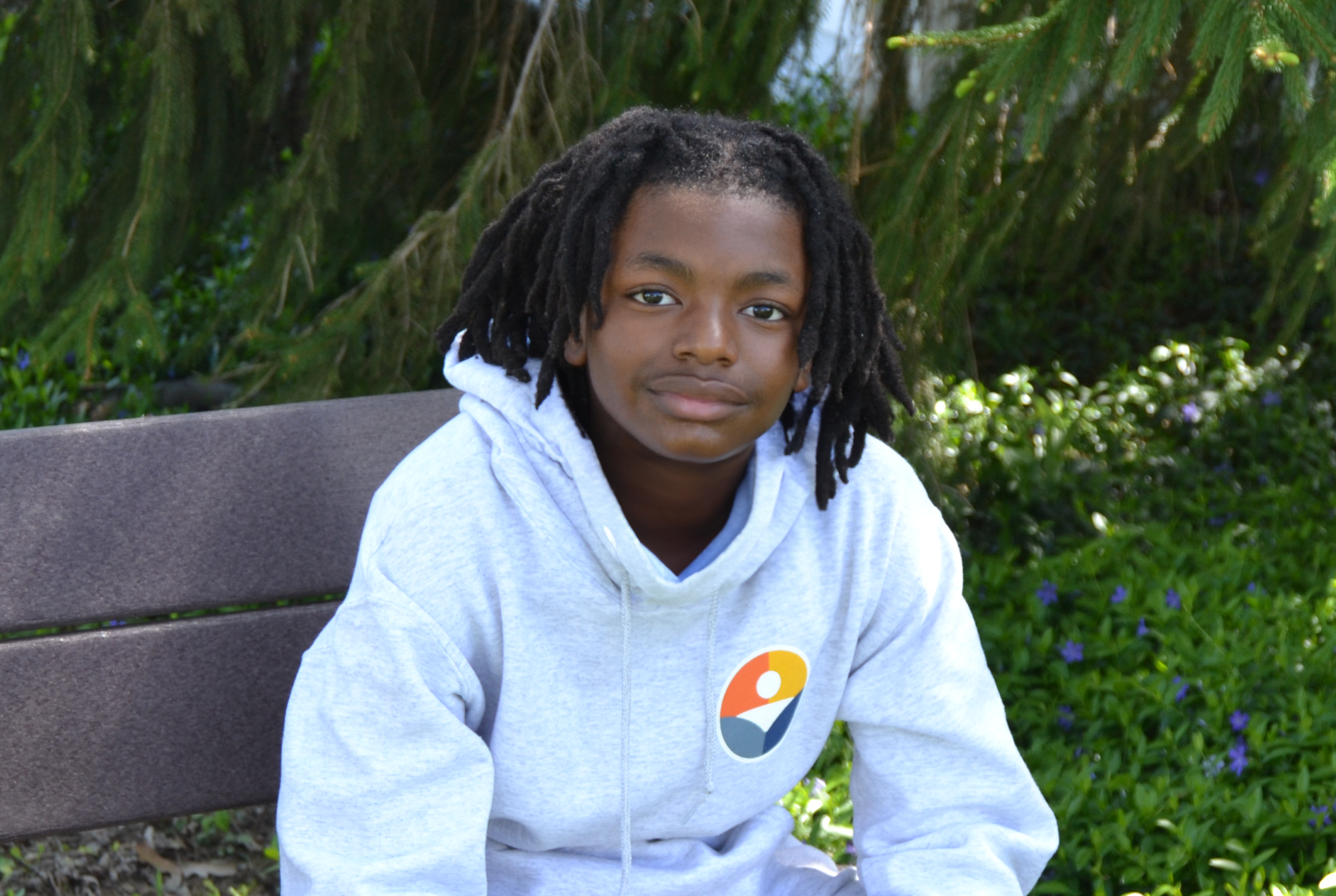 John Jackson wearing a white hoodie sitting on a bench outside.